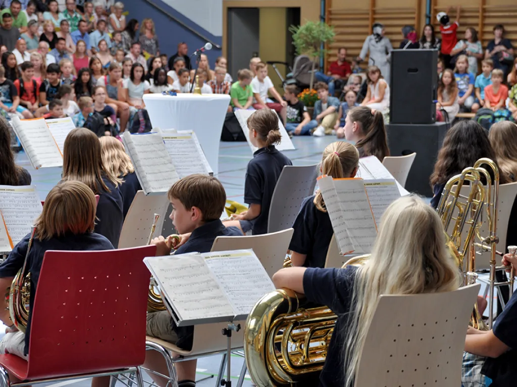 Die Bläserklasse spielt an Notenständern in der Sporthalle.